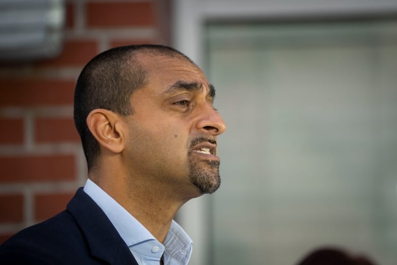 A South Asian man with short-cropped hair is pictured in profile.