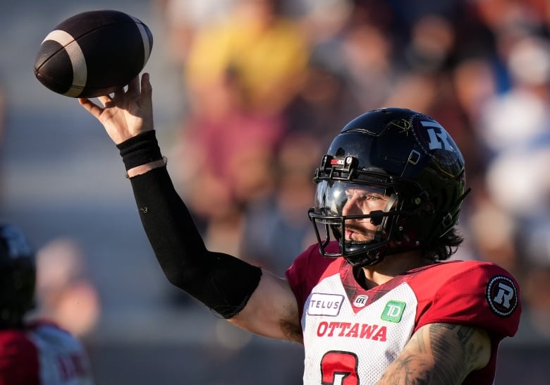 An athlete with his arms raised holding a ball during a Canadian Football game. 