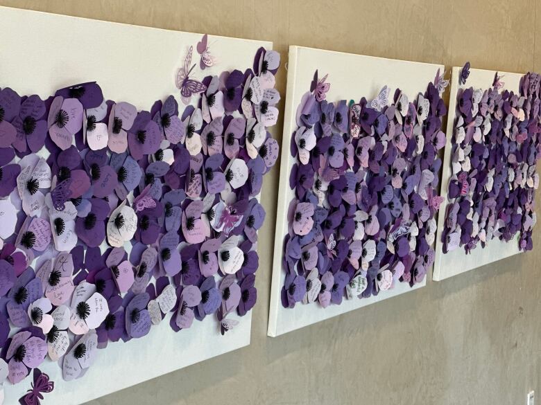 White panels with purple poppies sit on a wall.