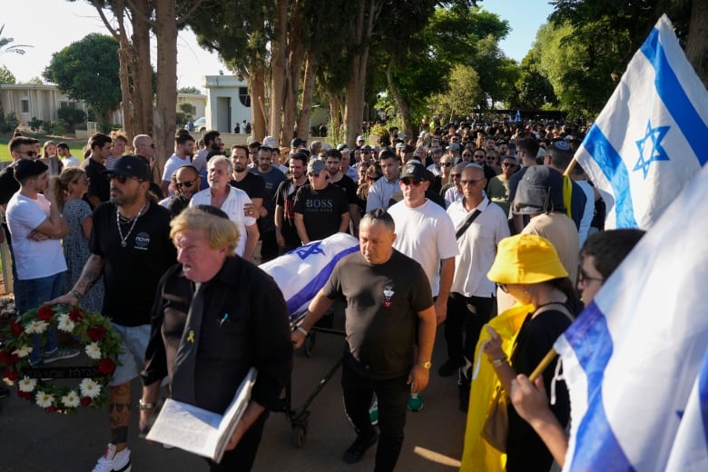 People attend a funeral for killed hostage Almog Sarusi in Ra'anana, Israel.