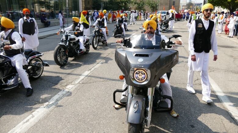 Two rows of people riding motorcycles while matching outfits.