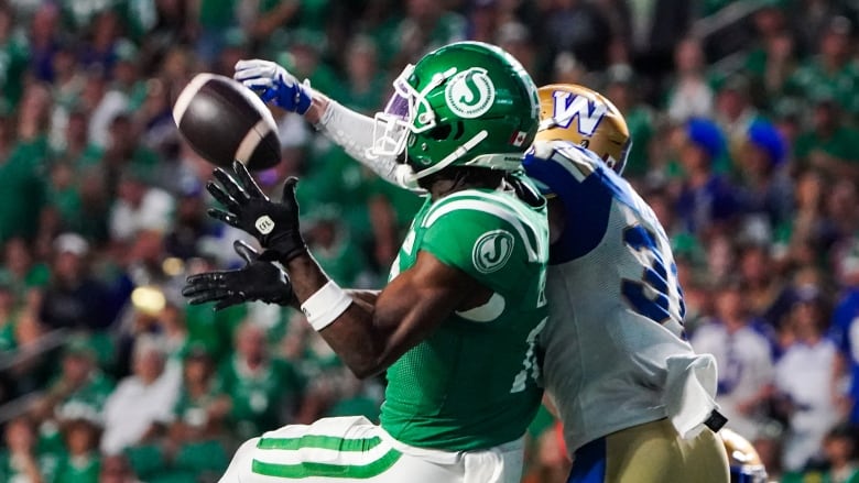 Two people in football gear clash while trying to grab the ball