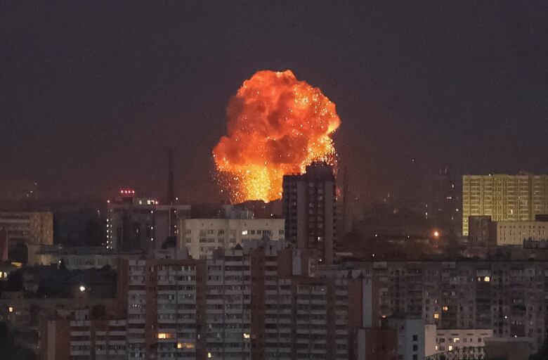 An explosion is seen in the dark sky over a city.