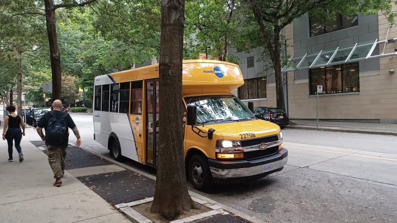 A yellow and white minibus parked on a city street.