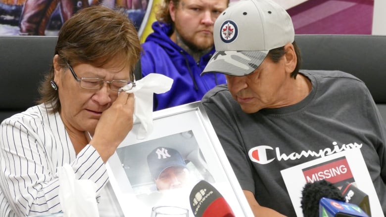 A woman holding a photo frame cries.