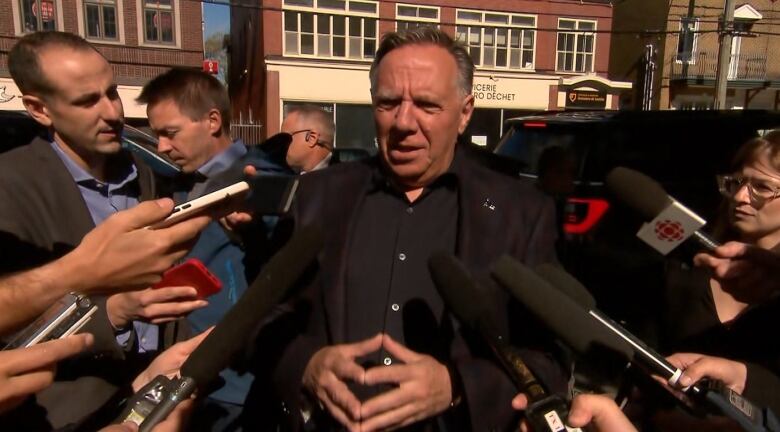 a middle aged white man surrounded by microphones and reporters