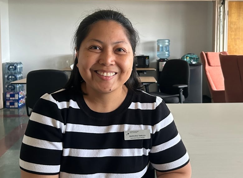 A smiling woman wearing a striped shirt and a name tag that says 