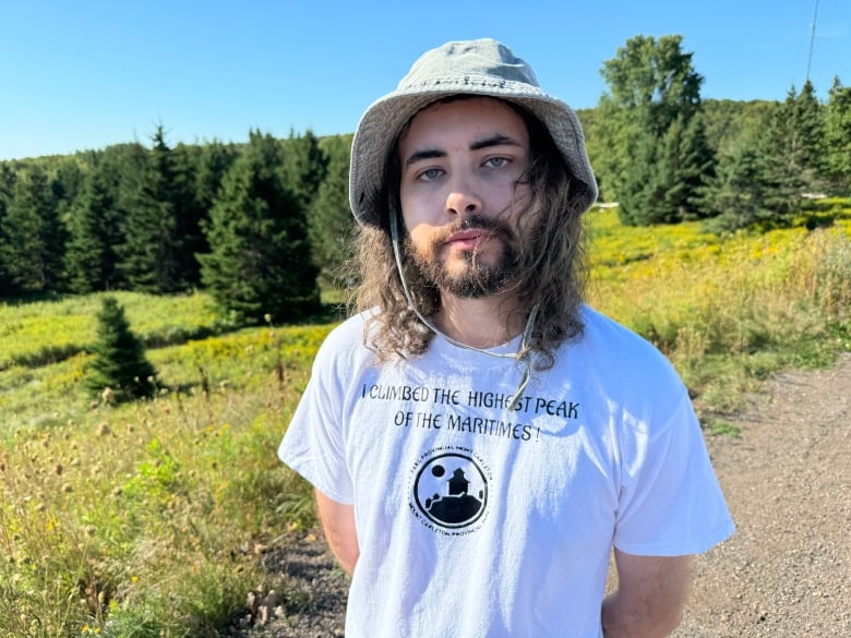 A man stands in front of some trees.