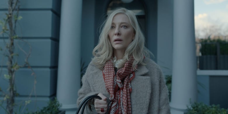 Cate Blanchett stands in a peacoat with a scarf.