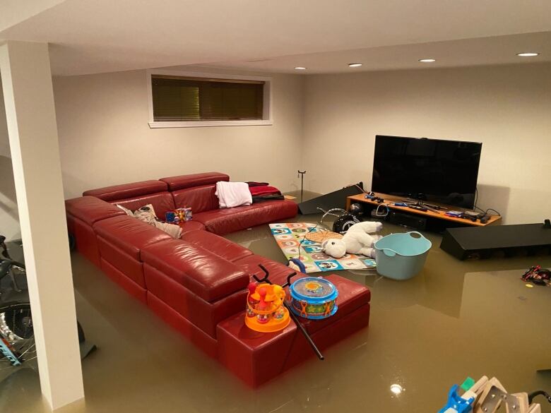 A couch and some household objects in a basement are seen floating in two feet of brown water.