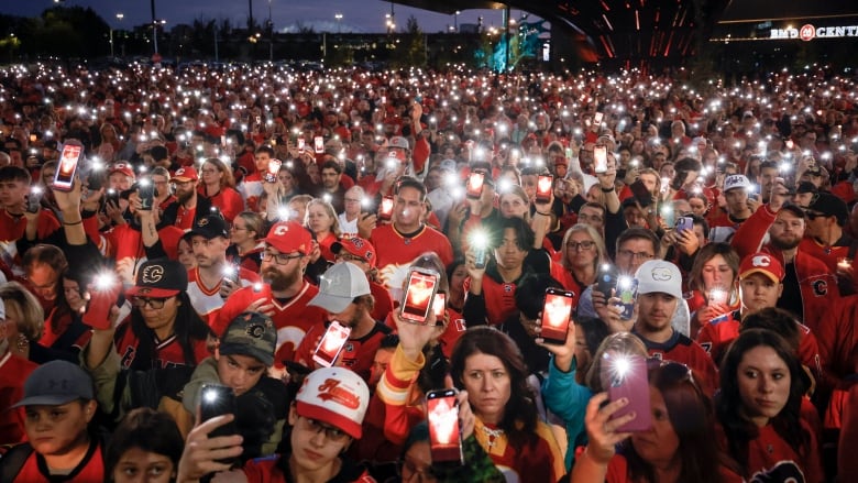 A group of people hold phones in the dark. 