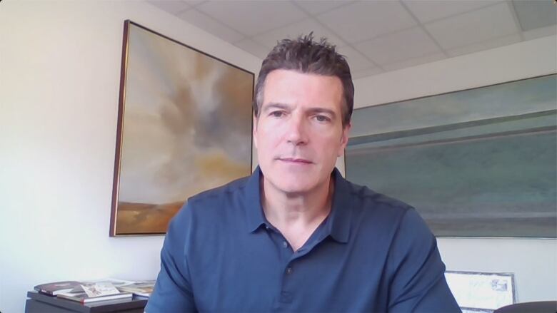 A man wearing a blue dress shirt sits in an office.