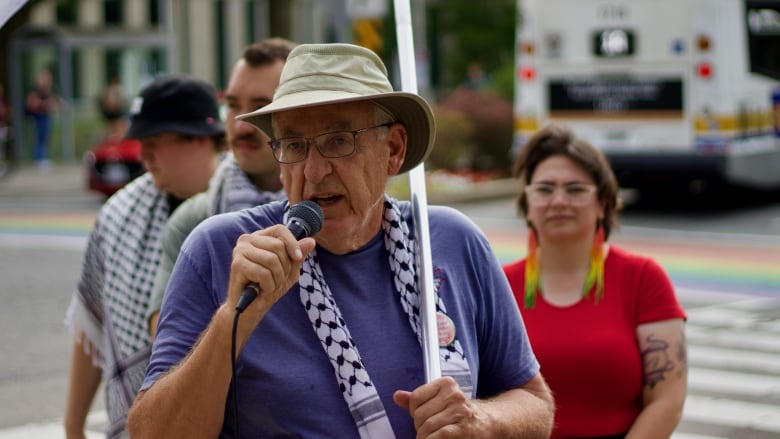 A person in a sun hat speaks into a microphone.