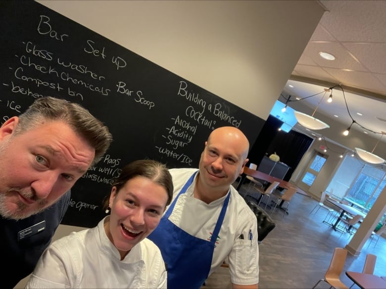 Three people stand together and take a selfie. Two of them wear chefs clothing.