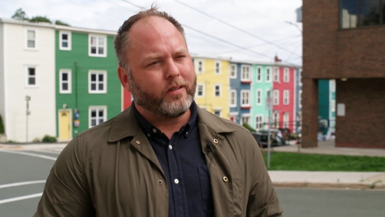 Man stands in front of colourful row houses