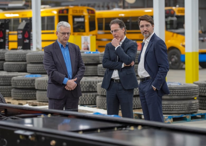 Prime Minister Justin Trudeau, MP Stephane Lauzon and CEO Marc Bedard look at the chassis of an electric school bus at the Lion Electric assembly facility in Saint-Jerome, Que. northwest of Montreal.