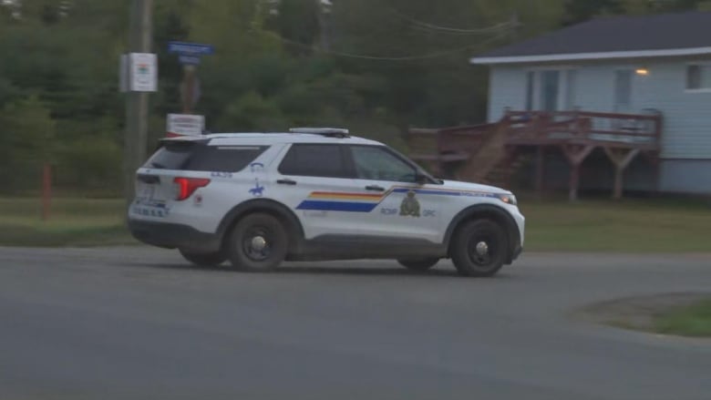 A marked RCMP SUV turning onto a road at dusk.