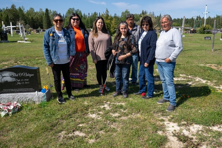 A gorup of people stand together in a cemetery.