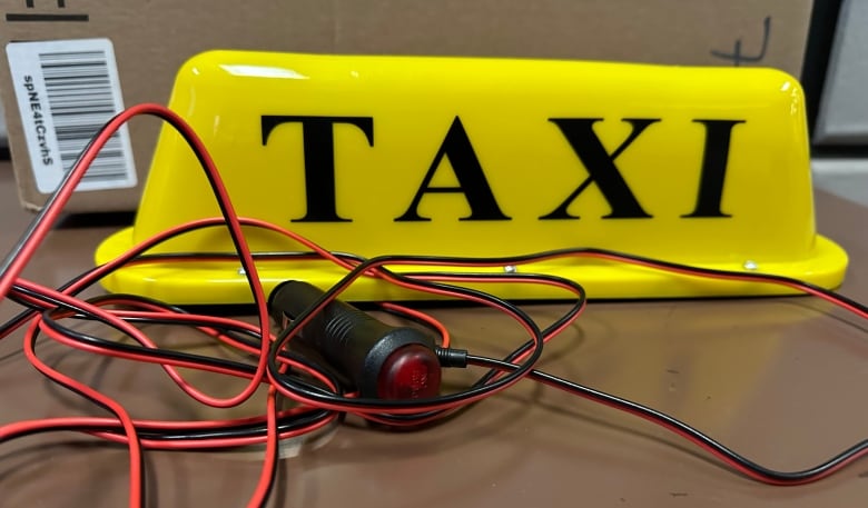 A yellow taxi sign with an attached wire. 