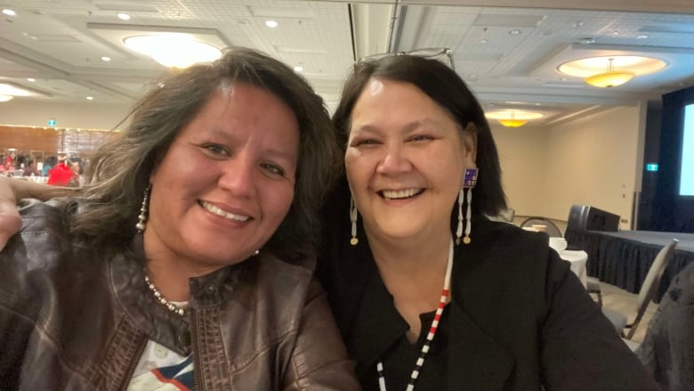 Two women sit smiling at a table.