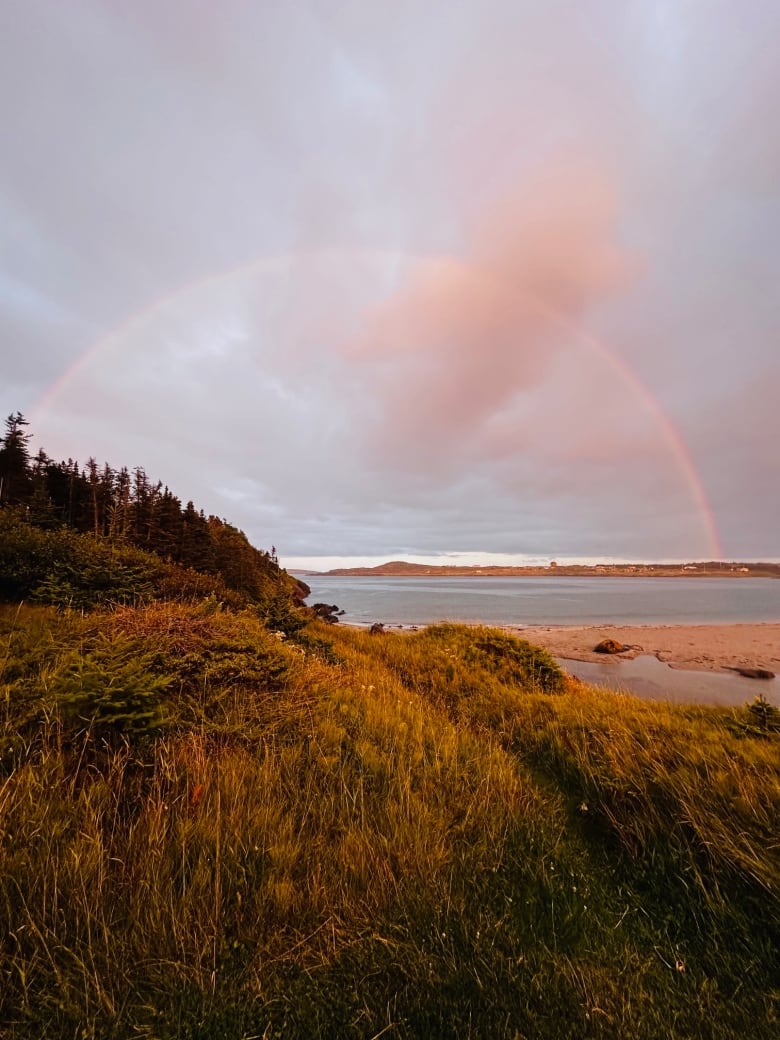 A rainbow can be seen over an island. 