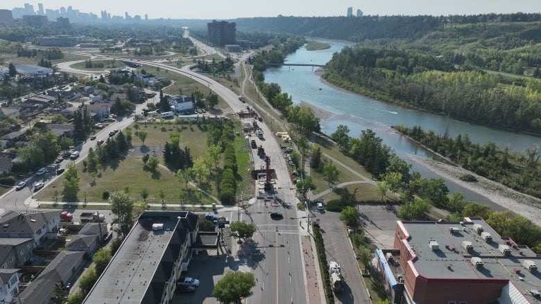 Construction work on Calgary's 16th avenue can be seen and a blue river runs alongside the road.