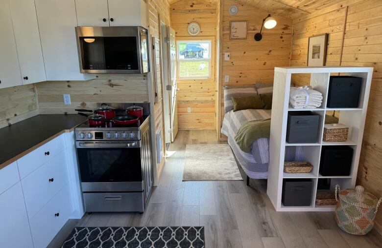 Interior of small home showing bed on the right and a kitchen on the left of the photo. 