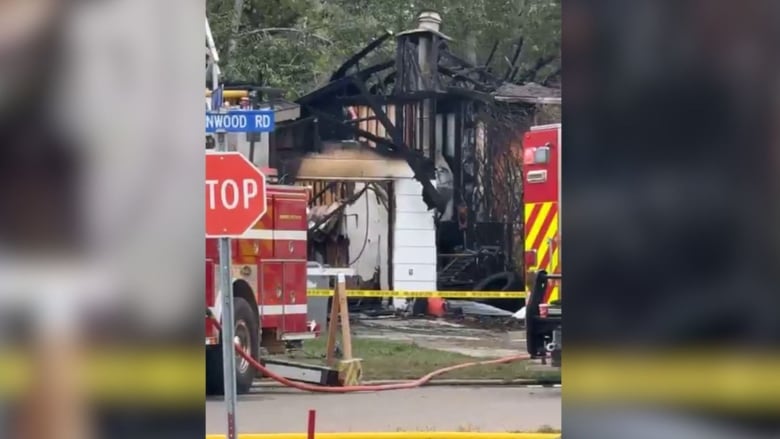 A photo shows a charred house with fire engines close by.