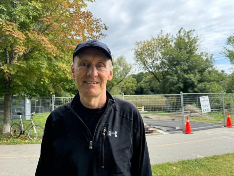 A man is standing outside of a construction zone near a waterfront where a dock is being built 