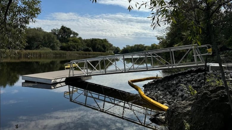 A steep dock reaching out into the river that is still under construction. 