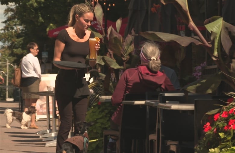 A young woman serves an older woman a beer on a patio.