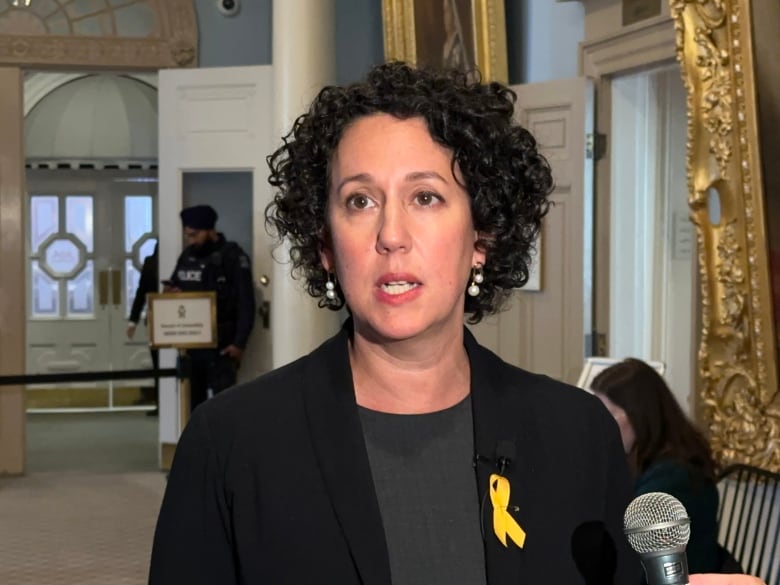 Woman with dark hair and yellow ribbon pin 