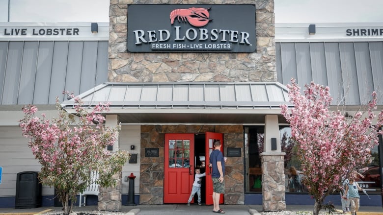 The front of a building is shown, with people entering through a red door. Above the door is the lettering 'Red Lobster,' followed by 'Fresh Fish, Live Lobster.'