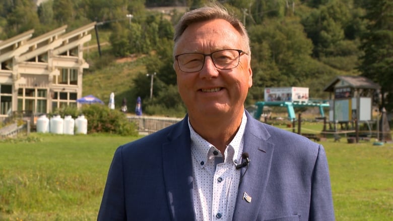 A man wearing a suit standing at the base of a ski hill. 