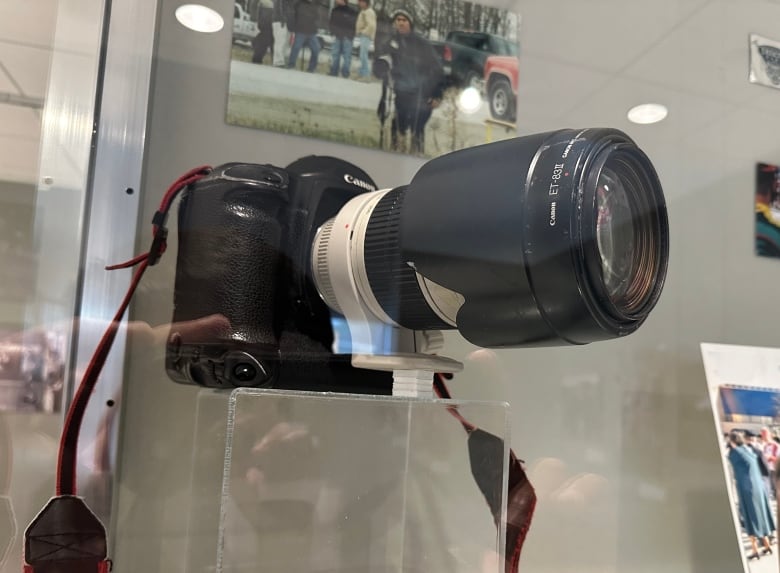 A camera with a long lens in a glass case.