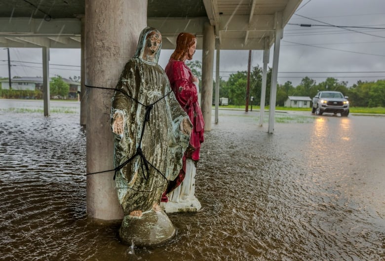 A statue is tied to a pillar in the rain.