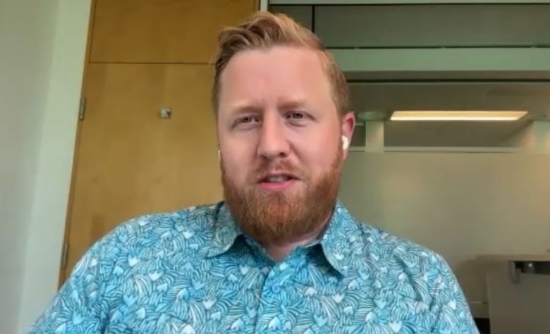 A photo of Ryan Schaap, a white man with orange hair and a blue shirt.