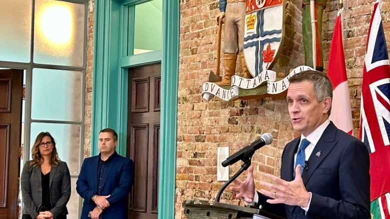 Mayor Mark Sutcliffe speaks to reporters at Ottawa city hall in September 2024 as city manager Wendy Stephanson and chief financial officer Cyril Rogers look on.