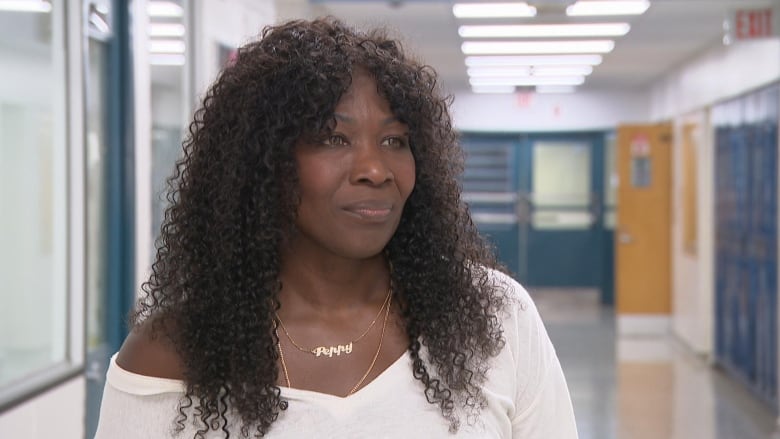 Karen Samuels, a middle-aged Black woman, standing in the hallway at Weston Collegiate Institute wearing a white shirt 