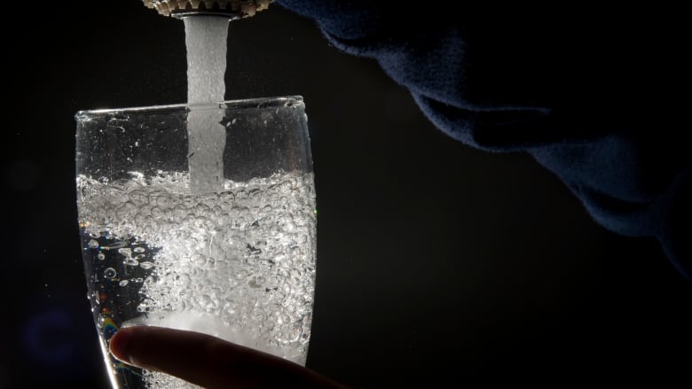 Drinking water is poured into a glass from a faucet 