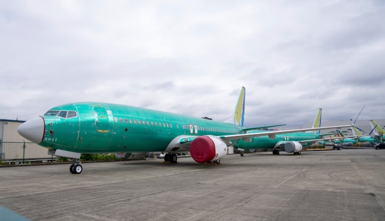 An aquamarine jetliner sits on a runway.