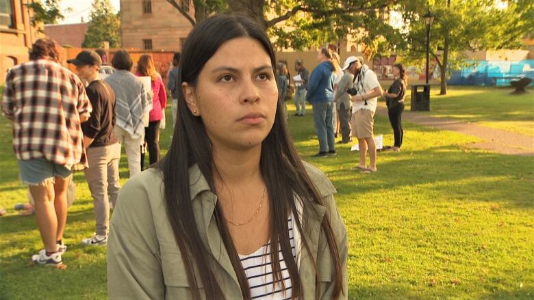 Maria Gomez standing outside with protesters in the background.