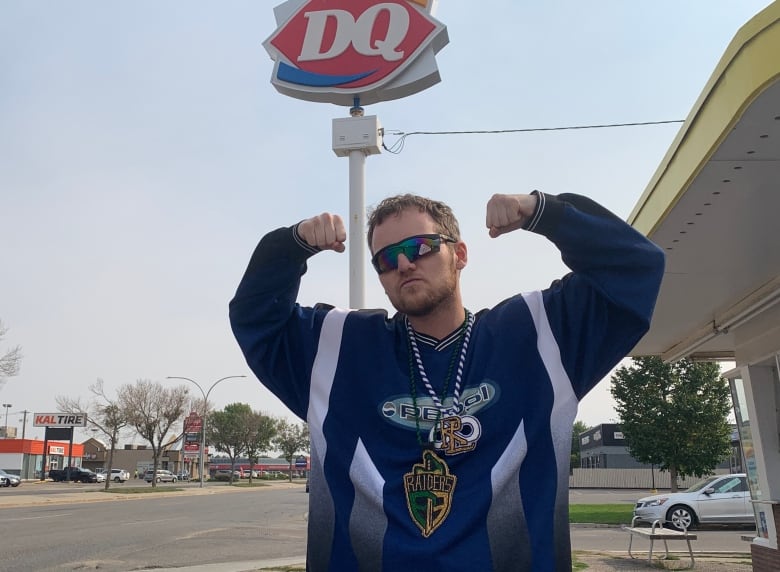 A man flexing his arms outside of a fast food drive-thru during the day.