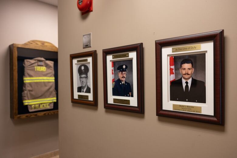 Three portraits of firefighters killed in the line of duty hang on the wall of a hall. Nearby is a shadow box with the brown jacket of a firefighter, with Skyler Blackie's name on it.