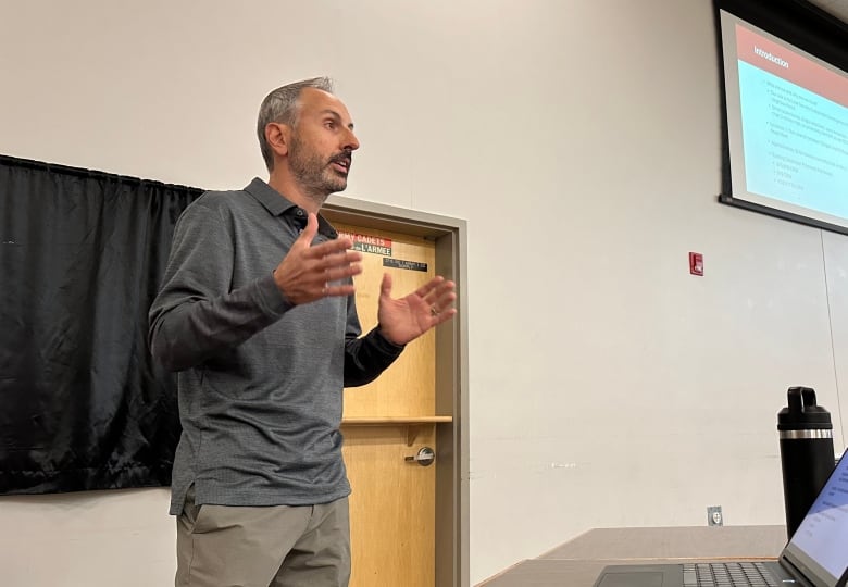 A man speaks before an audience at a citizens' meeting.