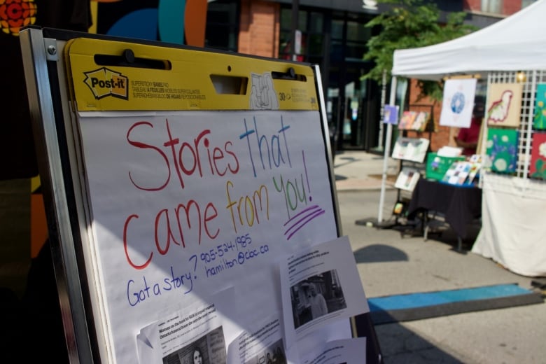 A sign on chart paper outdoors reading 'Stories that come from you.' 