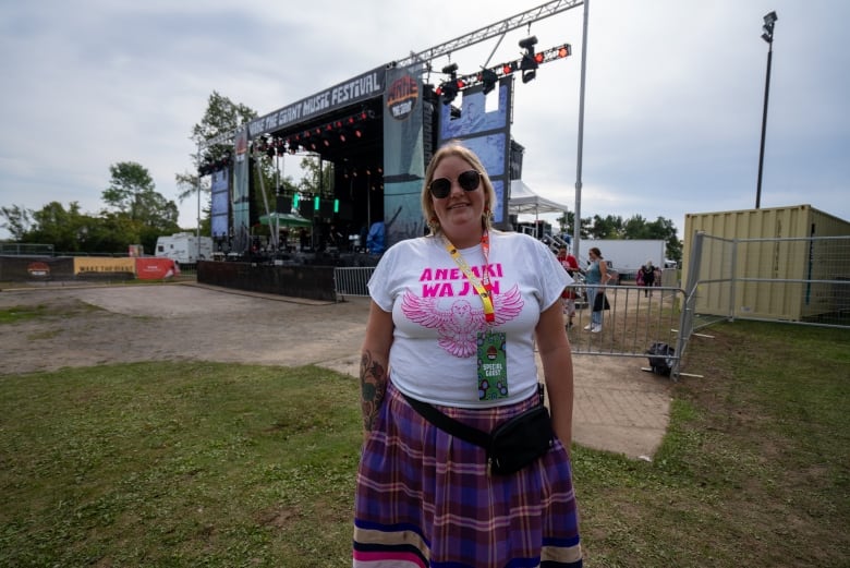 A person wearing a skirt is seen standing outside, with a stage set up behind them.