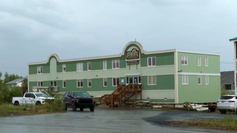 A green and white building, pictured on a rainy day.