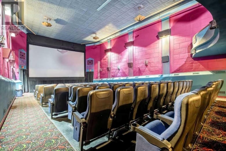 rows of chairs in a movie theatre face a large screen.