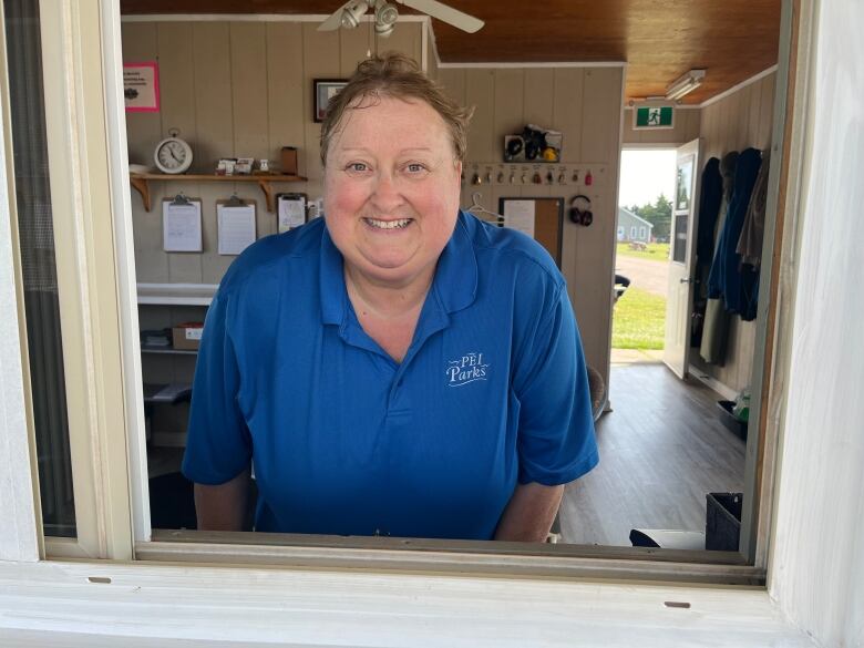 Woman in blue shirt looking out from window.